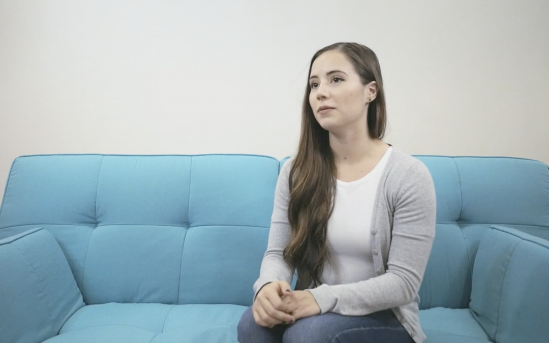 woman sitting on a blue couch speaking about improved results from Thrive