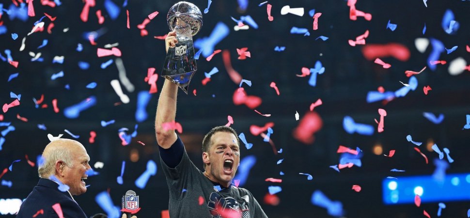 Tom Brady holding Superbowl trophy as colorful confetti falls