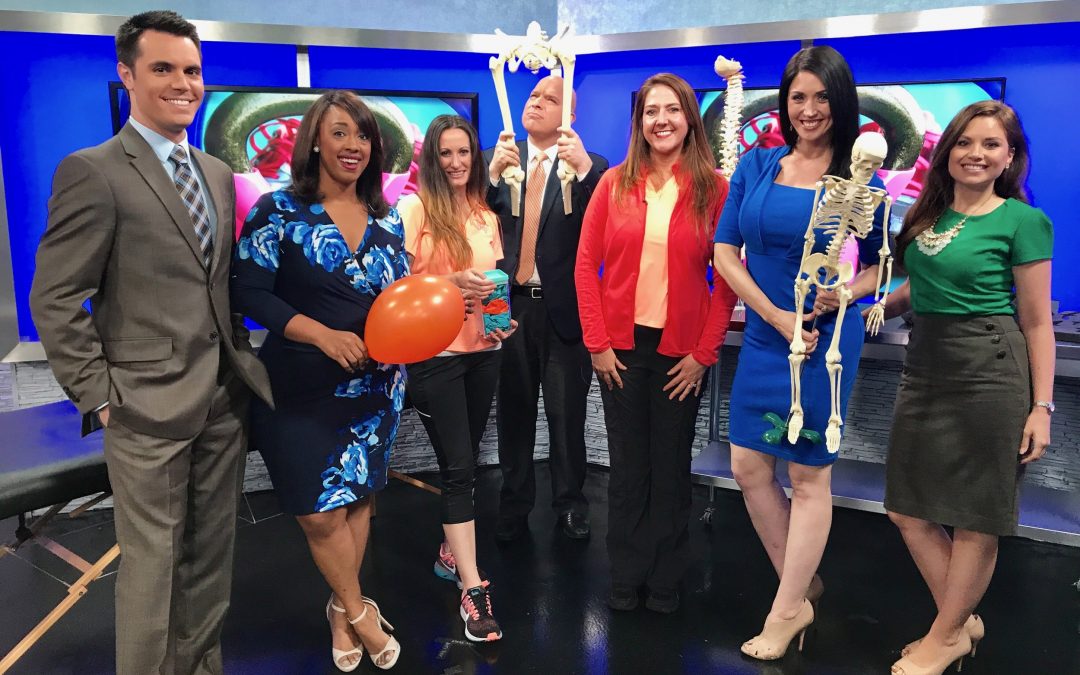 Kristen Crowley and WGNT/WTKR News 3 morning crew on set holding balloon and skeleton pieces