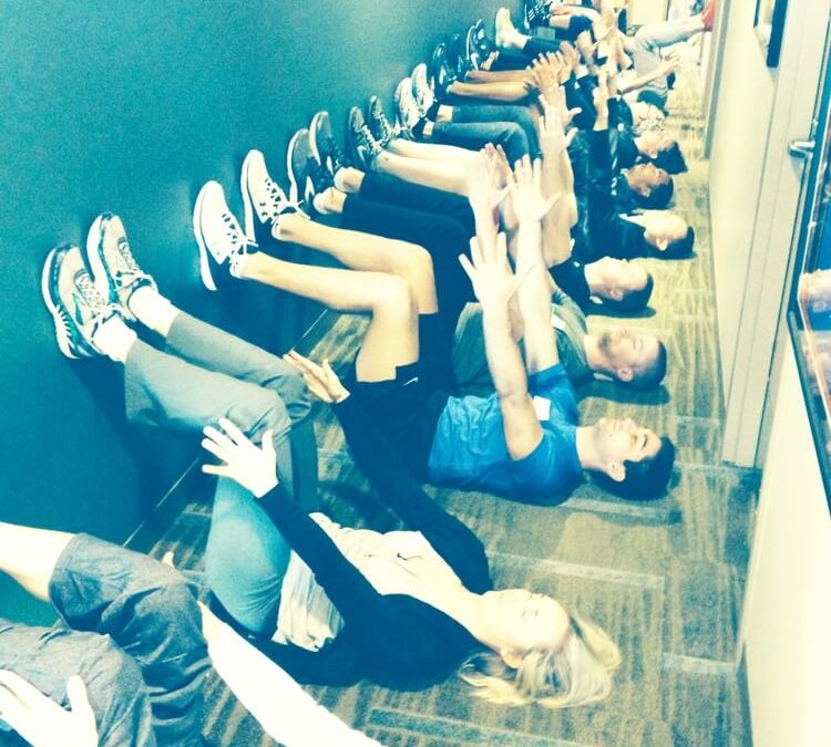 group of people laying down on backs in a line with feet against wall