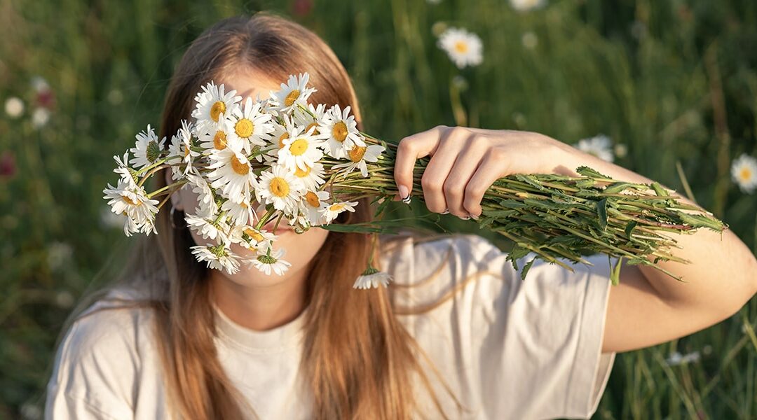 Young woman holding a bouquet of wild flowers in front of her face